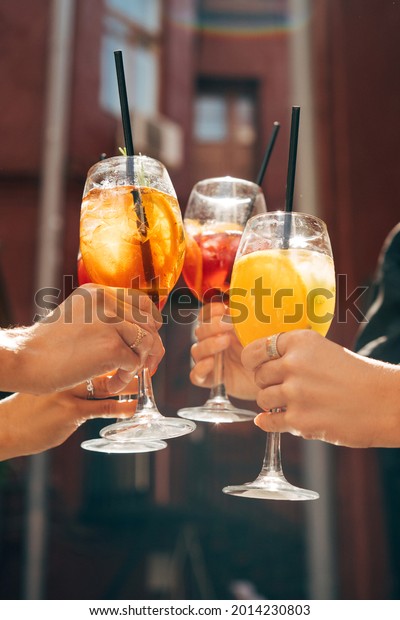 Friends toasting, saying cheers\
holding tropical cocktails. Making celebratory toast\
