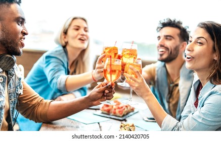 Friends toasting spritz at cocktail bar restaurant - Trendy life style concept with young people having fun together toasting fancy drinks on happy hour time - Backlight filter with focus on glasses - Shutterstock ID 2140420705