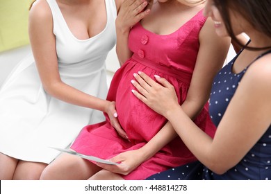 Friends touching pregnant woman's belly at baby shower party