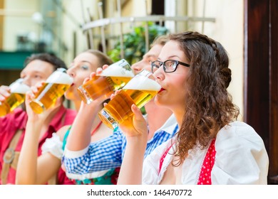 Friends In Traditional Bavarian Tracht In Restaurant Or Pub With Beer In Bavaria, Germany