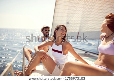 Friends traveling together on vacation. Smiling people and men sailing on yacht.