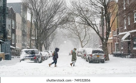 Friends Trek Through A Snow Covered Street In Brooklyn During A Blizzard. 