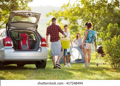 
Friends Unpacking Car For Camping Trip In Countryside