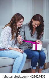 Friends Unwrapping A Gift In Living Room At Home