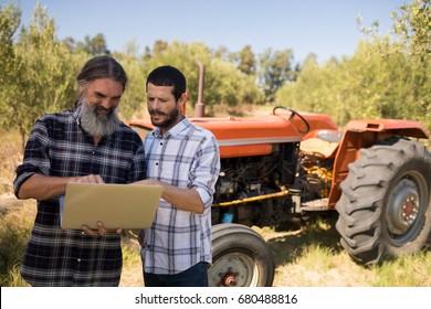 Friends using laptop in farm on a sunny day - Powered by Shutterstock