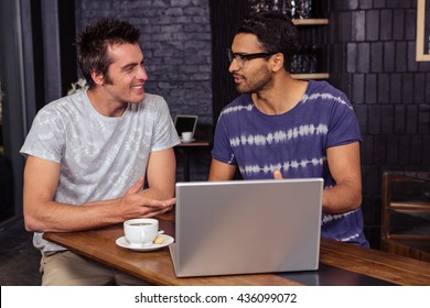 Friends using a laptop while talking in a coffee shop - Shutterstock ID 436099072