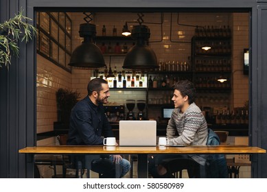 Friends Using Mobile And Laptop In A Coffee Shop.