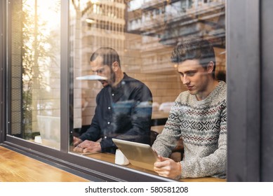 Friends Using Mobile And Laptop In A Coffee Shop.