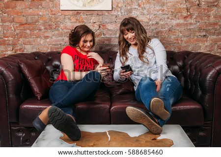 Friends using phone while sitind on sofa at living room Technology, education and friendship concept