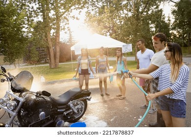 Friends washing motorcycle at charity car wash - Powered by Shutterstock