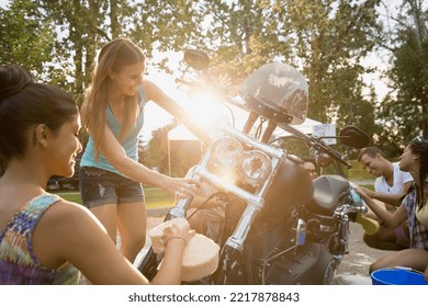 Friends washing motorcycle at charity car wash - Powered by Shutterstock