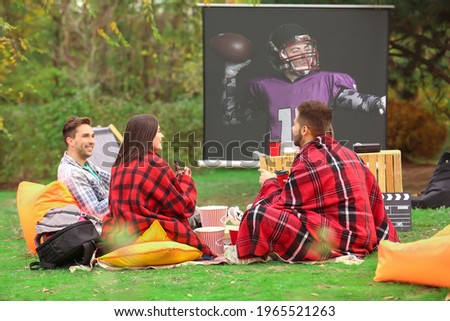 Friends watching American football in outdoor cinema