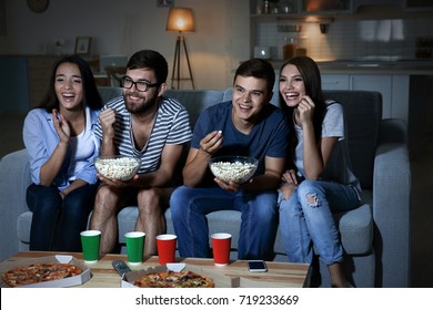 Friends watching TV in evening at home