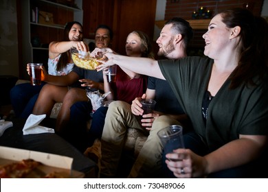 Friends Watching Tv At Night Passing Around Snacks