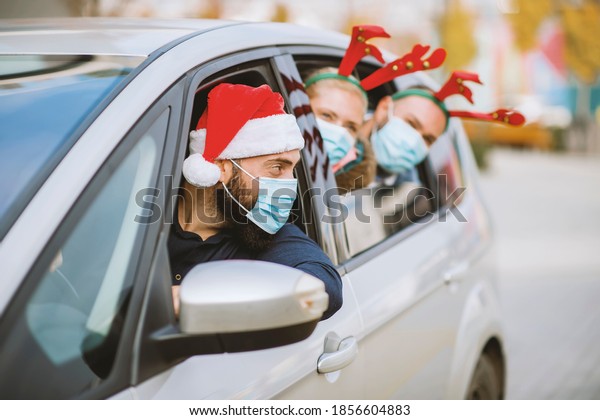 Friends wearing a protective face mask in the\
car. Holidays during epidemic.\
