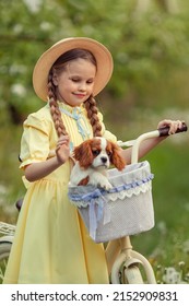 Friendship of children and pets. a cute girl and a little puppy cavalier ride a bike in spring in a blooming garden