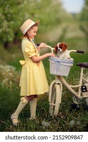 Friendship of children and pets. a cute girl and a little puppy cavalier ride a bike in spring in a blooming garden
