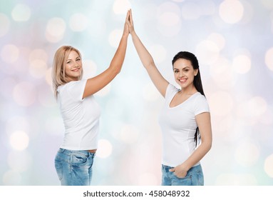 friendship, diverse, body positive, gesture and people concept - group of happy different women in white t-shirts making high five over holidays lights background - Powered by Shutterstock