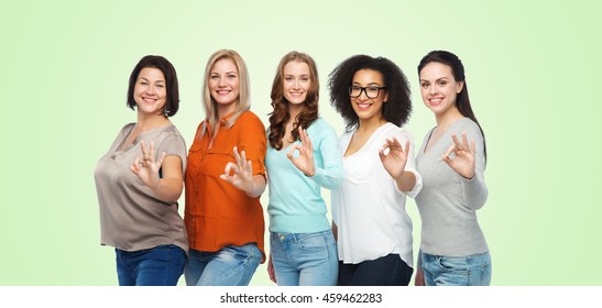 friendship, fashion, body positive, gesture and people concept - group of happy different size women in casual clothes showing ok hand sign over green natural background