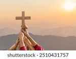 Friendship hands praying and holding Christian cross for worshipping God on mountain at sunrise background. Christian, Christianity, Religion copy space background. Easter Sunday concept: