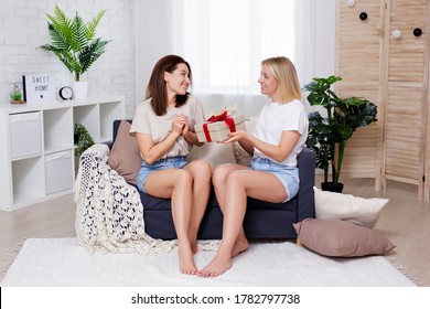 Friendship And Holidays Concept - Young Beautiful Woman Giving Gift Box To Her Best Friend