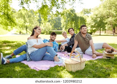 Friendship And Leisure Concept - Group Of Happy Friends With Non Alcoholic Drinks And Food At Picnic In Summer Park Looking Up