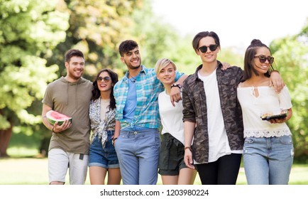 friendship and leisure concept - group of happy friends with watermelon and snack at summer park