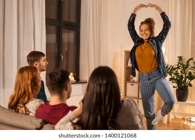 Friendship, Leisure And Entertainment Concept - Happy Friends Playing Charades Game At Home In Evening