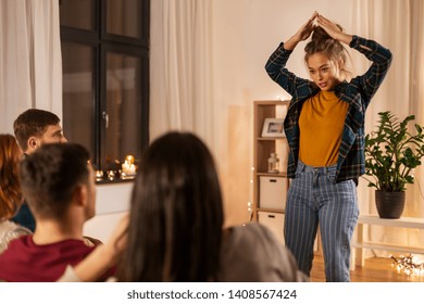 Friendship, Leisure And Entertainment Concept - Happy Friends Playing Charades Game At Home In Evening