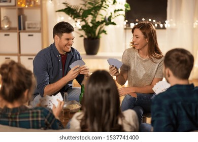 friendship, leisure and entertainment concept - happy friends with non-alcoholic beer playing cards game at home in evening - Powered by Shutterstock