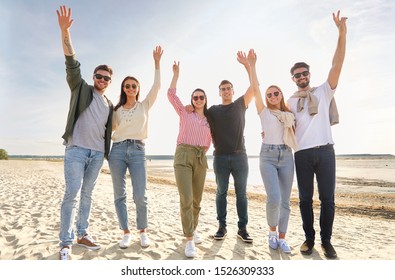 Friendship, Leisure And People Concept - Group Of Happy Friends Waving Hands On Beach In Summer