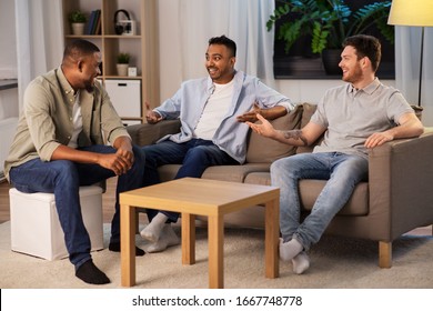 Friendship, Leisure And People Concept - Happy Smiling Male Friends Talking At Home At Night