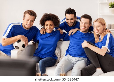 Friendship, Leisure, Sport And Entertainment Concept - Happy Friends Or Football Fans With Ball Watching Soccer On Tv At Home