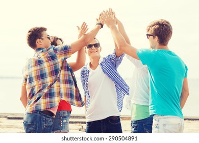 Friendship, Leisure, Summer, Gesture And People Concept - Group Of Smiling Friends Making High Five Outdoors