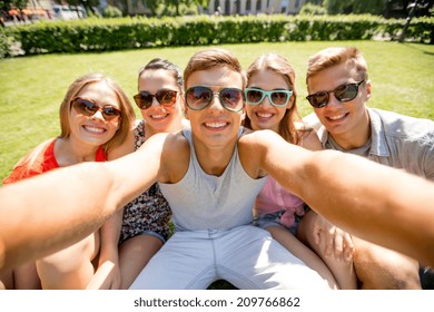 friendship, leisure, summer, technology and people concept - group of smiling friends making selfie with smartphone camera or tablet pc in park - Powered by Shutterstock