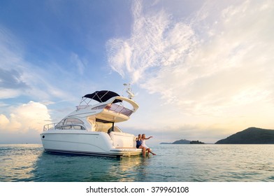 Friendship and luxury vacation. Two happy young women sitting on the yacht deck looking and pointing away sailing the sea. - Shutterstock ID 379960108