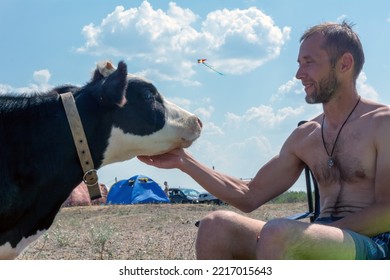 Friendship. Man Petting A Cow Against A Blue Sky