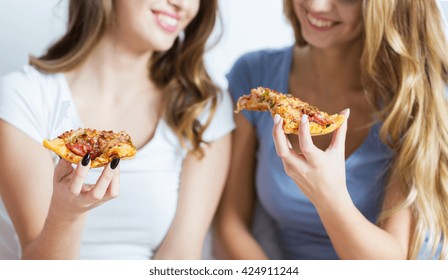friendship, people, pajama party and junk food concept - close up of happy friends or teenage girls eating pizza at home
