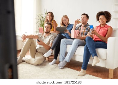 Friendship, People, Technology And Entertainment Concept - Happy Friends With Tablet Pc Computer And Smartphone Eating Popcorn, Drinking Beer Or Cider And Watching Tv At Home