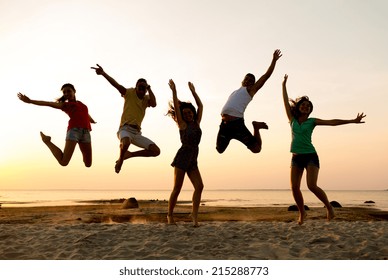 Friendship, Summer Vacation, Holidays, Party And People Concept - Group Of Smiling Friends Dancing And Jumping On Beach