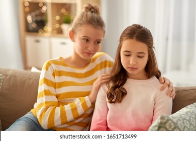 friendship, support and people concept - teenage girl comforting her sad friend at home