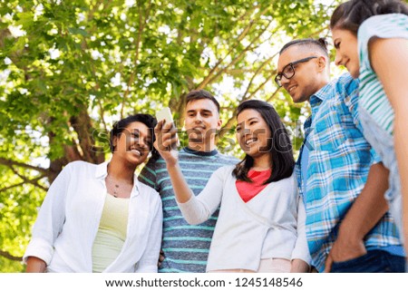 friendship, technology and international concept - group of friends with smartphone at summer park