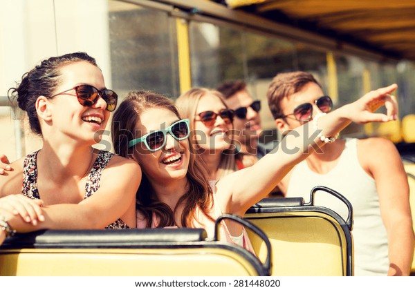 friendship, travel,\
vacation, summer and people concept - group of smiling friends\
traveling by tour\
bus