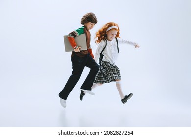 Friendship. Two Kids, School Boy And Girl, Brother And Sister Running Isolated On White Studio Background. Childhood, Dreams, Imagination, Education, Facial Expression, Emotions Concept. Copy Space