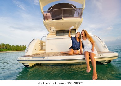 Friendship and vacation.  Young pretty women taking selfie togetherr on the yacht sailing the sea.