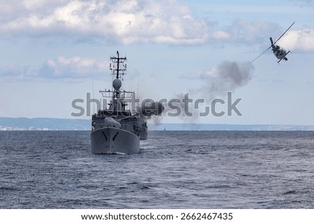 A frigate of Navy makes missile launch during fighting with military copter. War ship shoot with gun.	