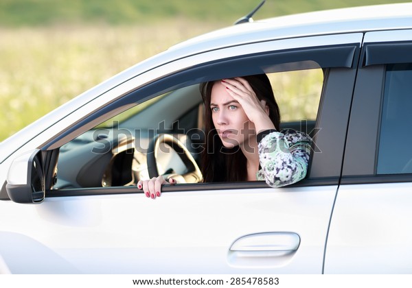 frightened  angry\
woman looking out  window of\
car