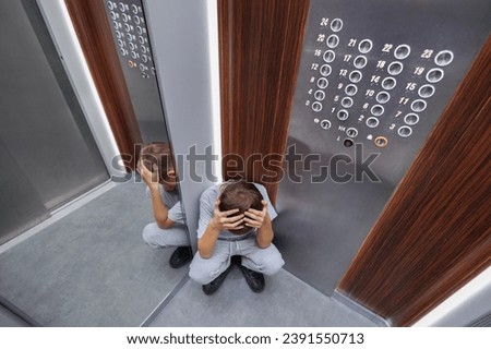 A frightened boy sits in a broken elevator and cries