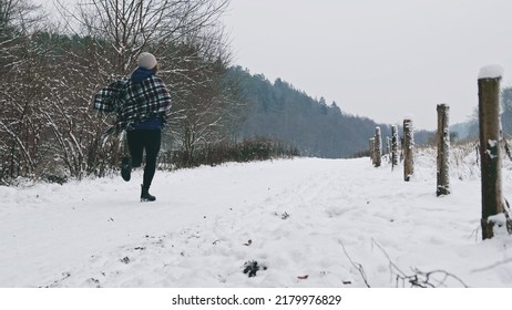 Frightened Caucasian Woman In Warm Blanket Coat Running Away From Threat Through Meadow Field Road Covered In Snow In The Middle Of Nowhere On Cold Winter Day