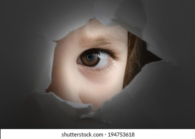 frightened child is spying through a hole in wall